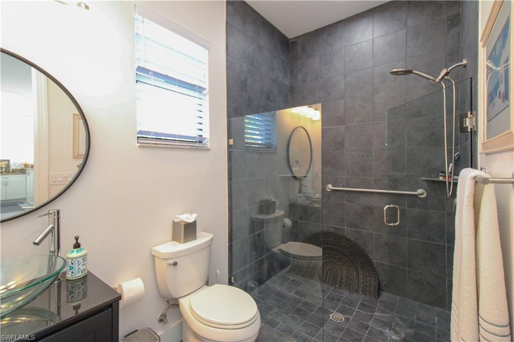 Bathroom featuring an enclosed shower, vanity, and toilet