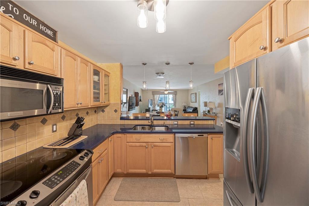 Kitchen featuring sink, light brown cabinets, decorative backsplash, light tile patterned flooring, and appliances with stainless steel finishes