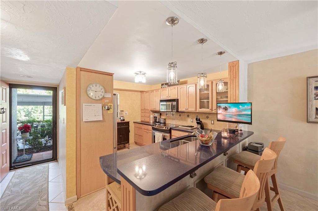 Kitchen featuring kitchen peninsula, appliances with stainless steel finishes, a breakfast bar, and light tile patterned flooring
