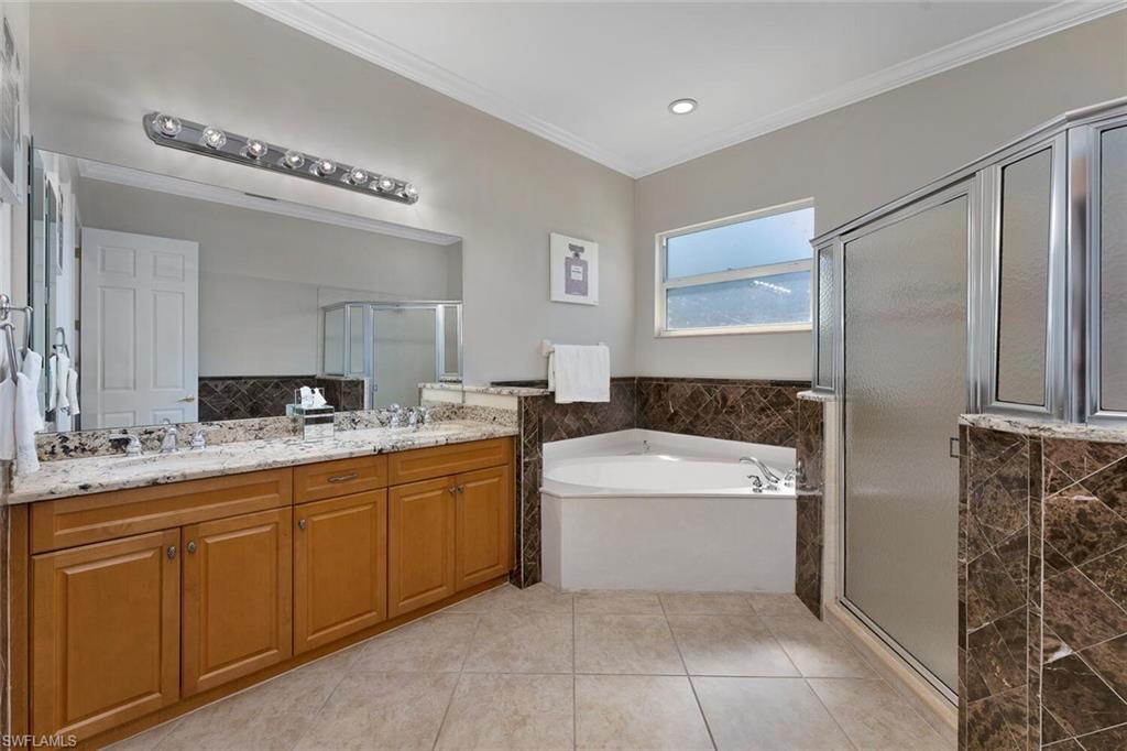Bathroom featuring tile patterned flooring, crown molding, a stall shower, a bath, and a sink