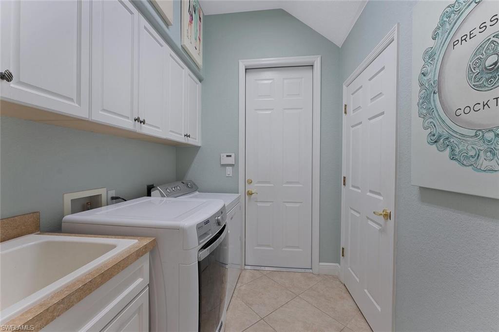 Washroom featuring light tile patterned floors, a sink, cabinet space, and separate washer and dryer