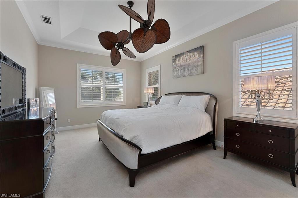 Bedroom with visible vents, crown molding, baseboards, light carpet, and a ceiling fan