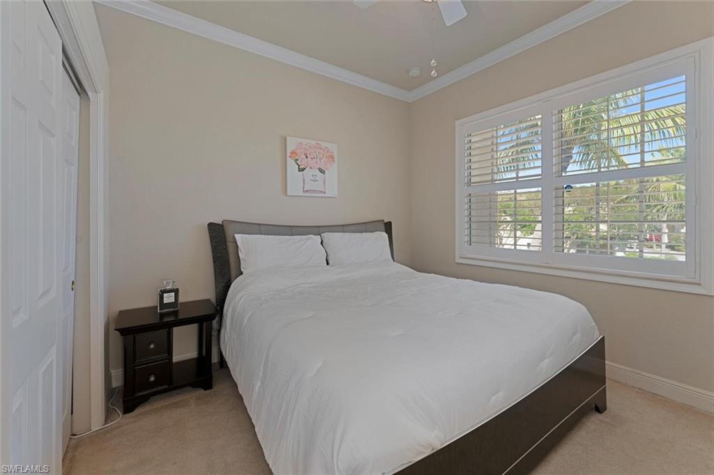 Carpeted bedroom with ceiling fan, baseboards, and ornamental molding
