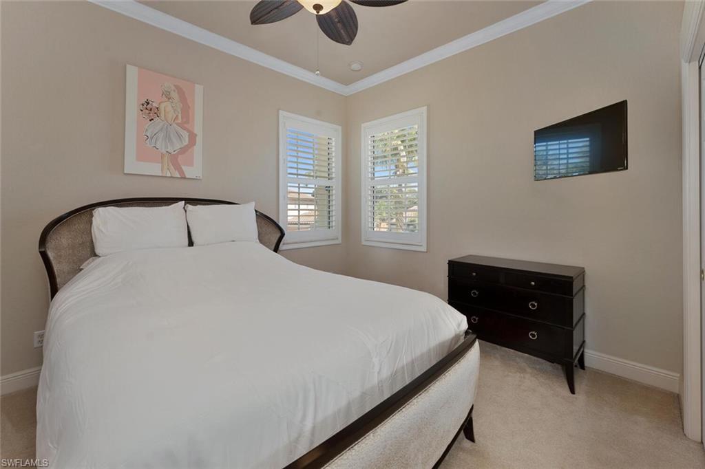 Bedroom with light colored carpet, a ceiling fan, crown molding, and baseboards