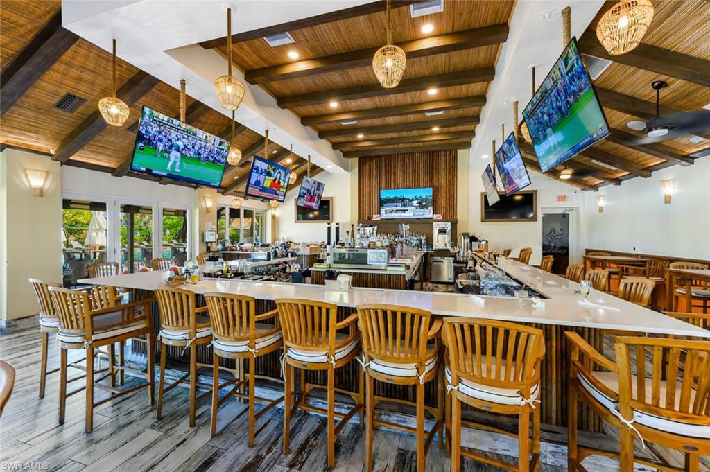 Bar with visible vents, beam ceiling, wood finished floors, a community bar, and wood ceiling
