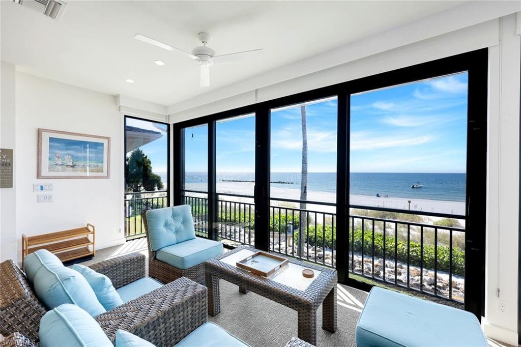 Sunroom / solarium featuring view of water and beach and recessed lighting