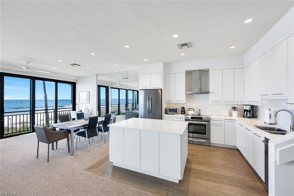 Kitchen with a center island, white cabinetry, stainless steel appliances, backsplash, and modern cabinets