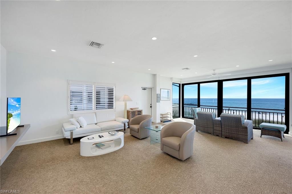 Living room featuring light carpet, a water view, recessed lighting, and ceiling fan