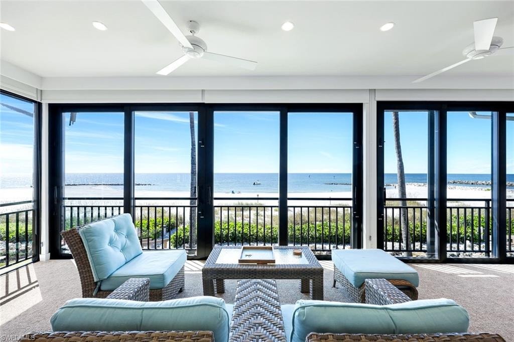Sunroom featuring carpet, view of water and beach, and recessed lighting