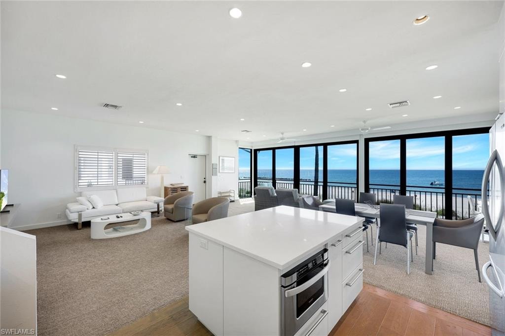 Kitchen featuring white cabinetry, open floor plan, a water view, stainless steel appliances, and recessed lighting