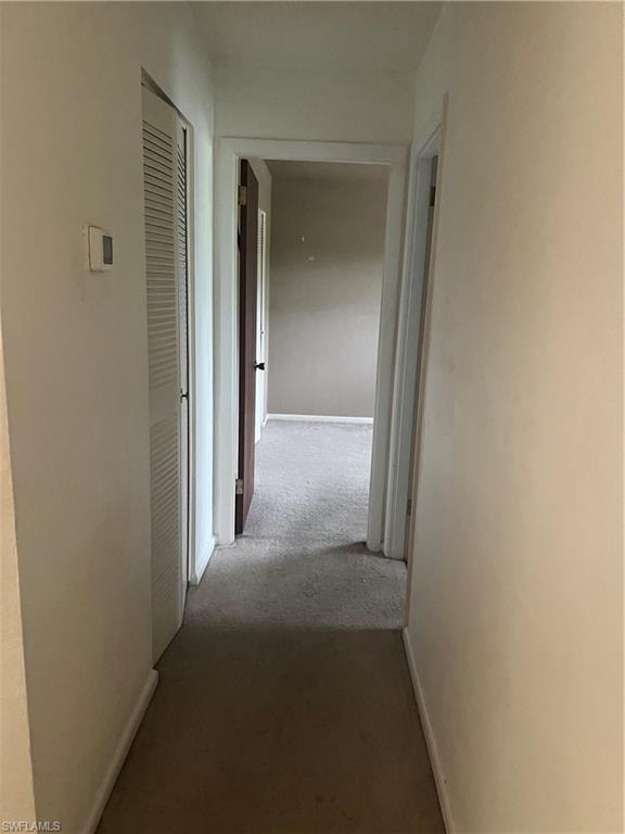 Hallway featuring carpet and baseboards