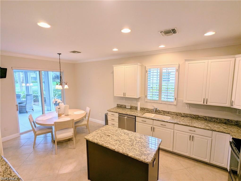 Kitchen featuring white cabinets, light stone countertops, recessed lighting, a kitchen island, and crown molding
