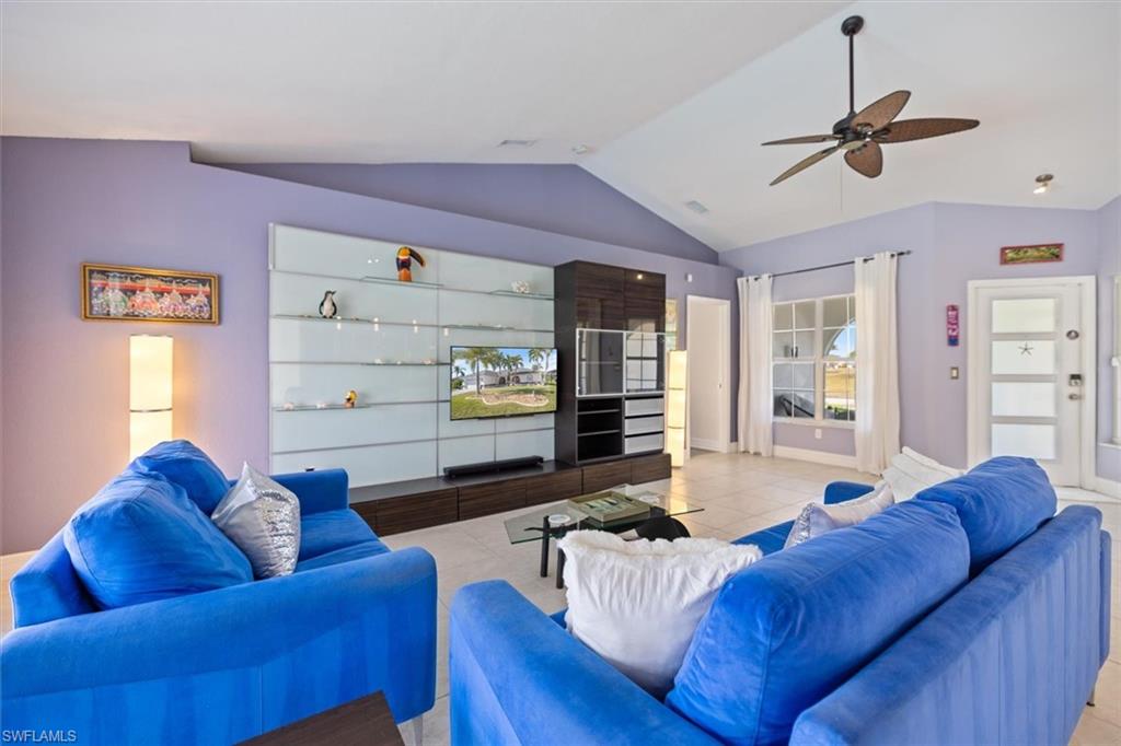 Living area featuring lofted ceiling, tile patterned flooring, and a ceiling fan
