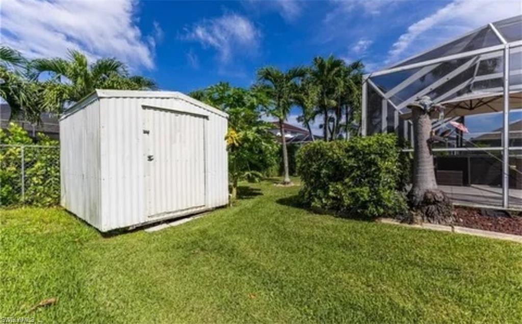 View of green lawn with a lanai, a sunroom, and a storage shed