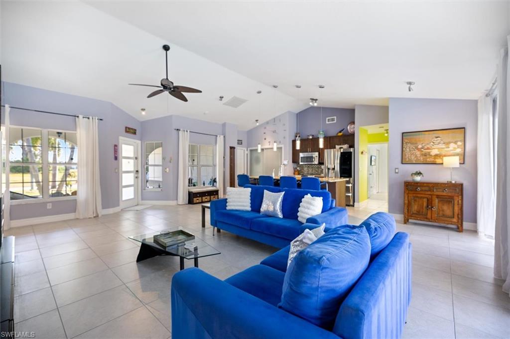 Living area with high vaulted ceiling, ceiling fan, and light tile patterned flooring