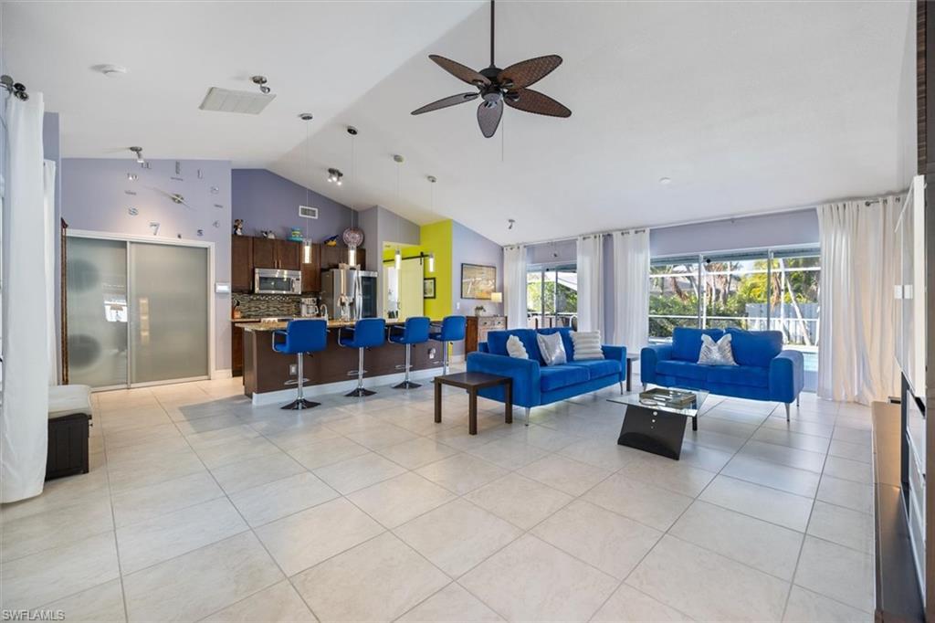 Living room with light tile patterned floors, high vaulted ceiling, and ceiling fan