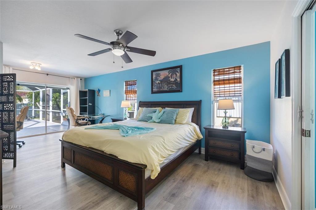 Bedroom featuring access to exterior, wood finished floors, and a ceiling fan