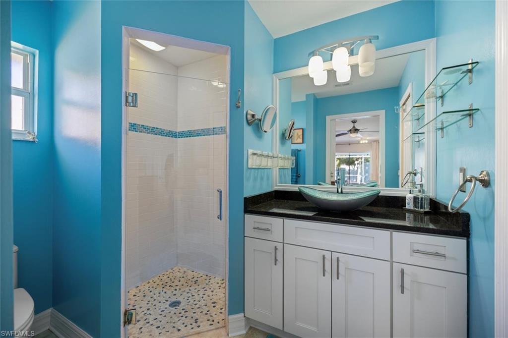 Full bath with vanity, a shower stall, and ceiling fan