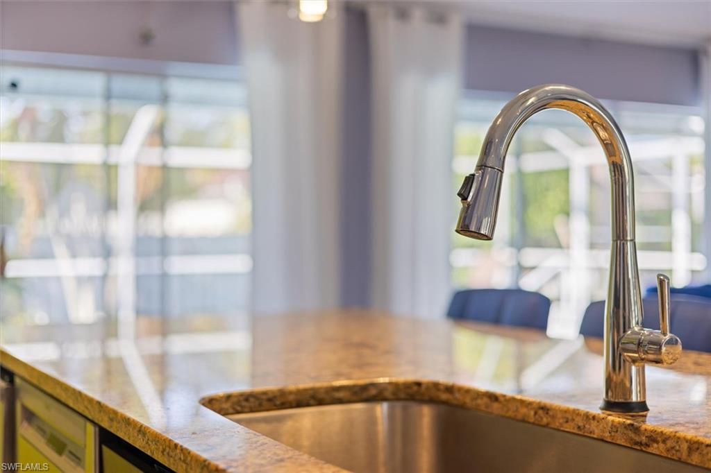 Kitchen view of a sink and light stone counters