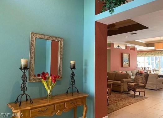 Hallway featuring a tray ceiling and light tile patterned flooring