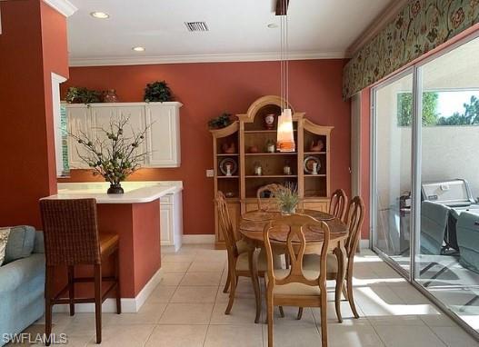 Dining space with light tile patterned floors and crown molding
