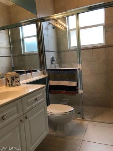 Bathroom featuring tile patterned flooring, vanity, a shower with shower door, and toilet