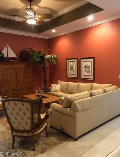Tiled living room featuring ceiling fan and ornamental molding