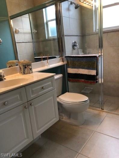 Bathroom with tile patterned flooring, vanity, an enclosed shower, and toilet