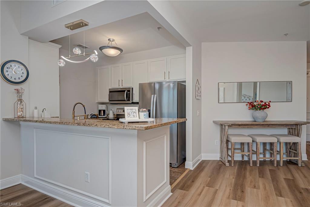Kitchen featuring stainless steel appliances, white cabinets, light tile patterned floors, and light stone countertops