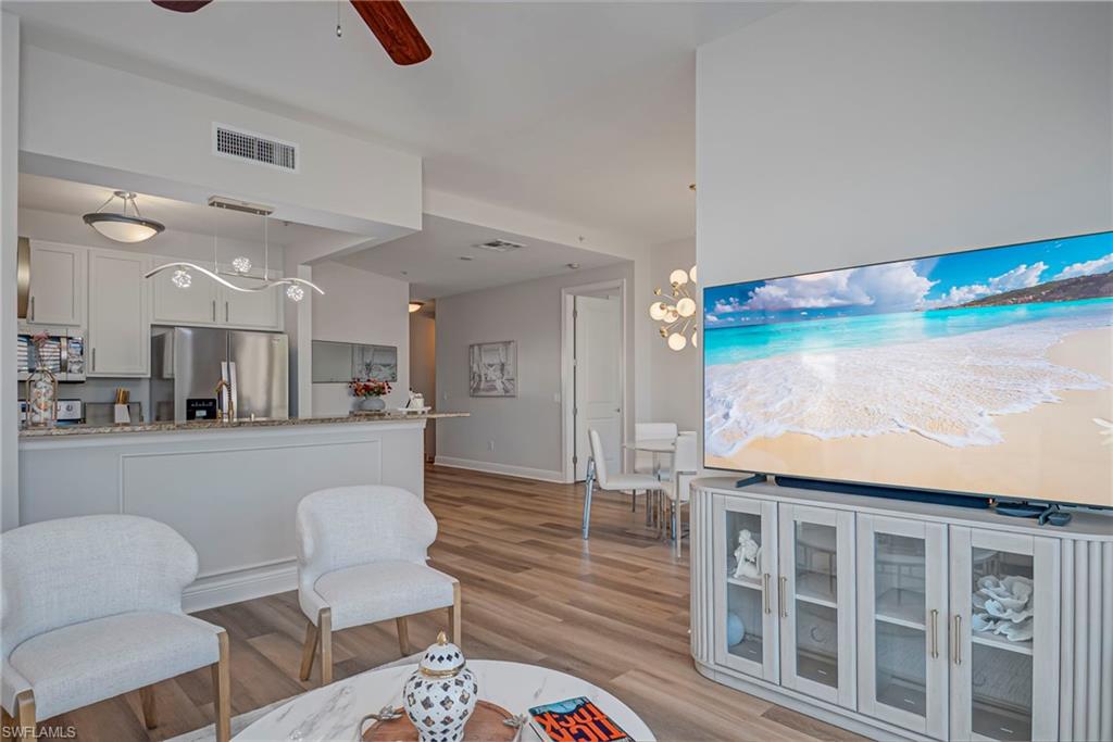 Kitchen featuring open floor plan, light floors, freestanding refrigerator, and white cabinets