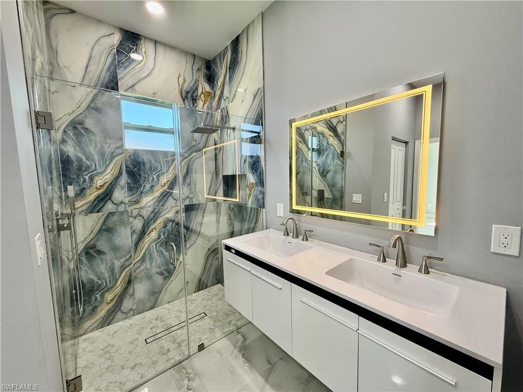 Unfurnished bedroom featuring a raised ceiling, light marble finish flooring, a ceiling fan, recessed lighting, and ornamental molding