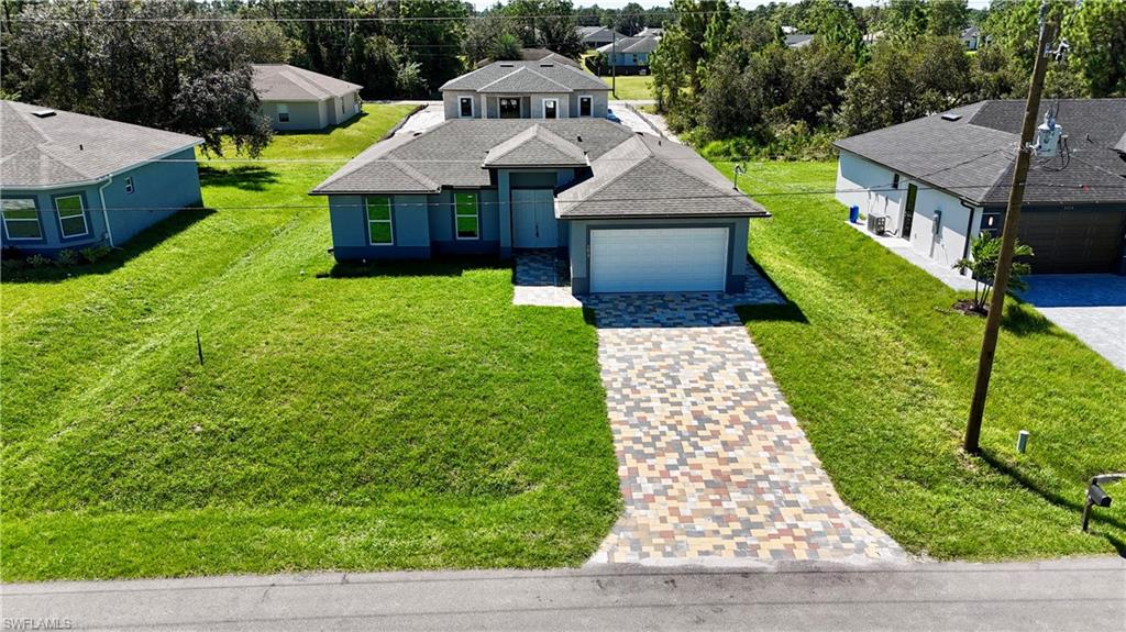 View of front of house featuring roof with shingles, driveway, and a front lawn