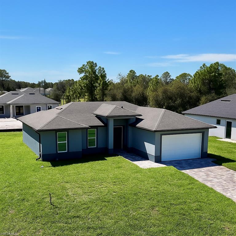 Single story home with a front lawn, decorative driveway, stucco siding, and a garage