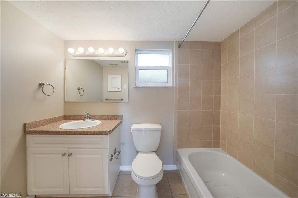 Full bath with vanity, light tile patterned flooring, and shower / washtub combination