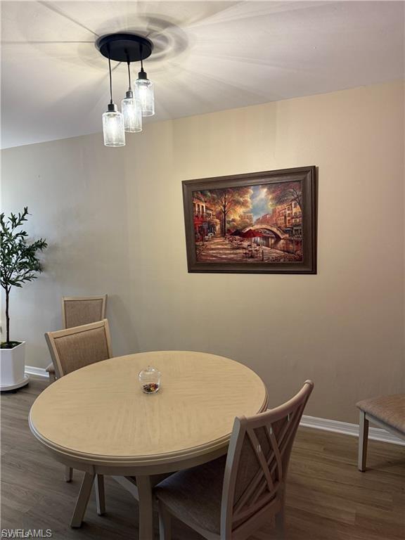 Dining area with dark wood-type flooring and baseboards