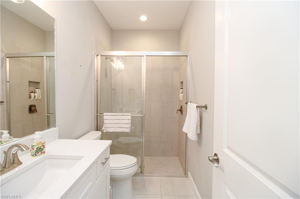 Bathroom featuring tile patterned floors, vanity, toilet, and walk in shower