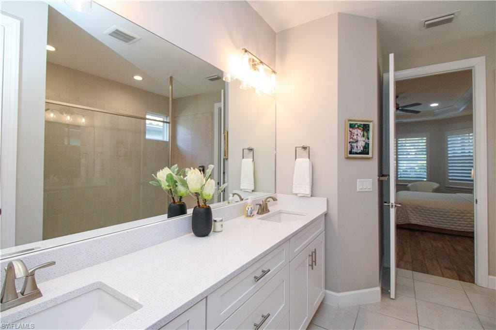 Bathroom with ceiling fan, tile patterned flooring, vanity, and tiled shower