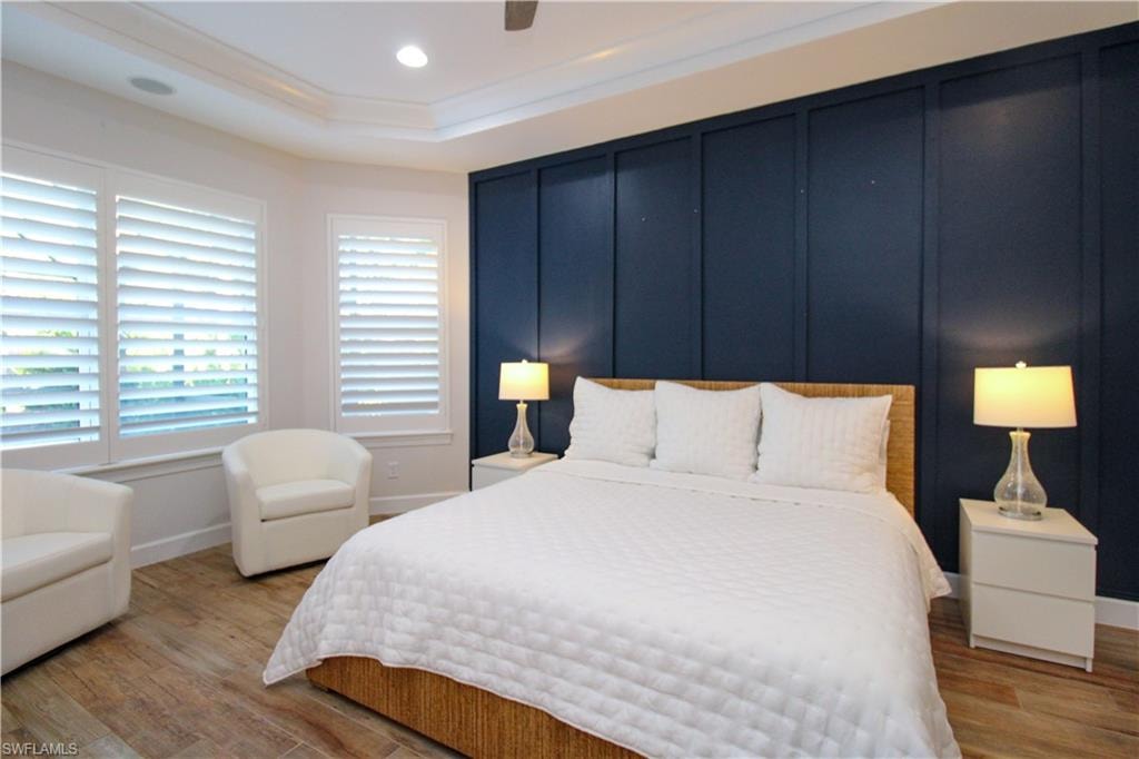Bedroom featuring ceiling fan, light hardwood / wood-style floors, ornamental molding, and a tray ceiling