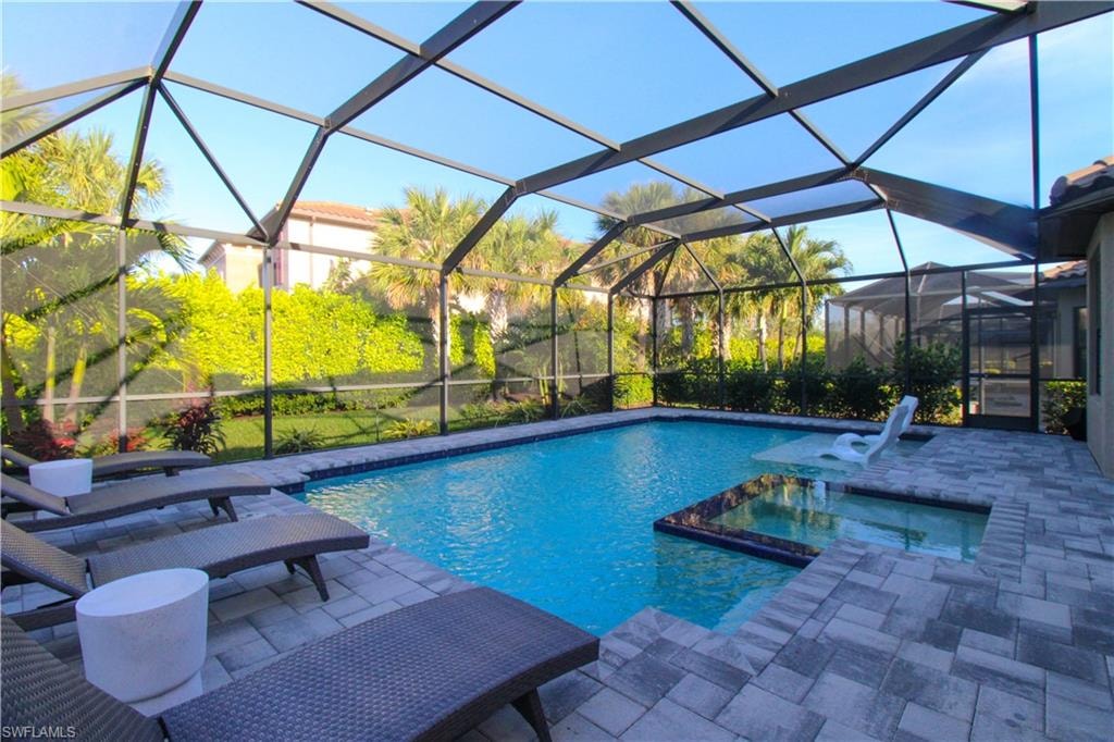View of swimming pool featuring an in ground hot tub, a patio, and glass enclosure