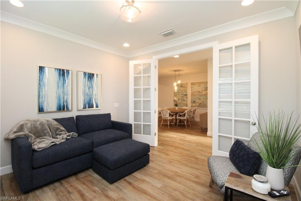 Living room with french doors, wood-type flooring, and ornamental molding