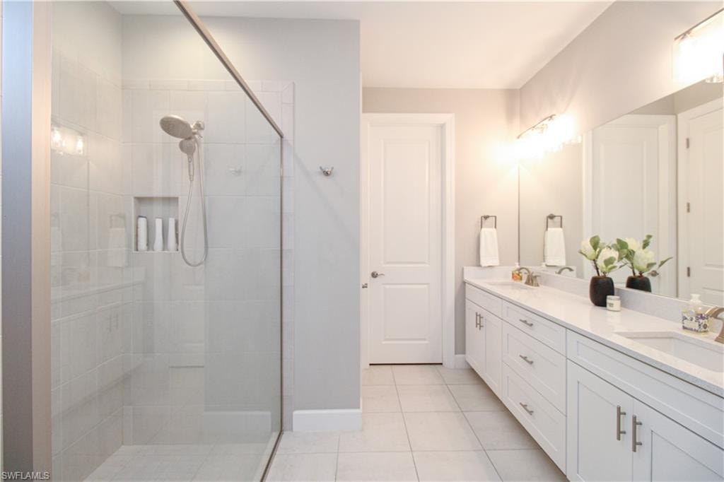 Bathroom featuring tile patterned floors, vanity, and tiled shower