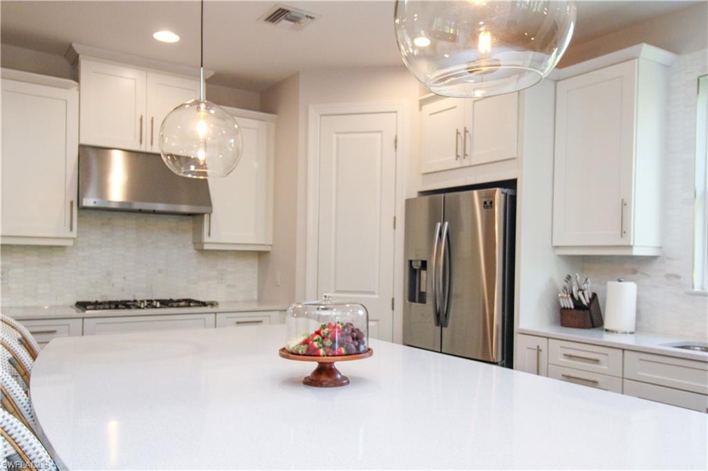 Kitchen featuring white cabinetry, stainless steel appliances, and tasteful backsplash