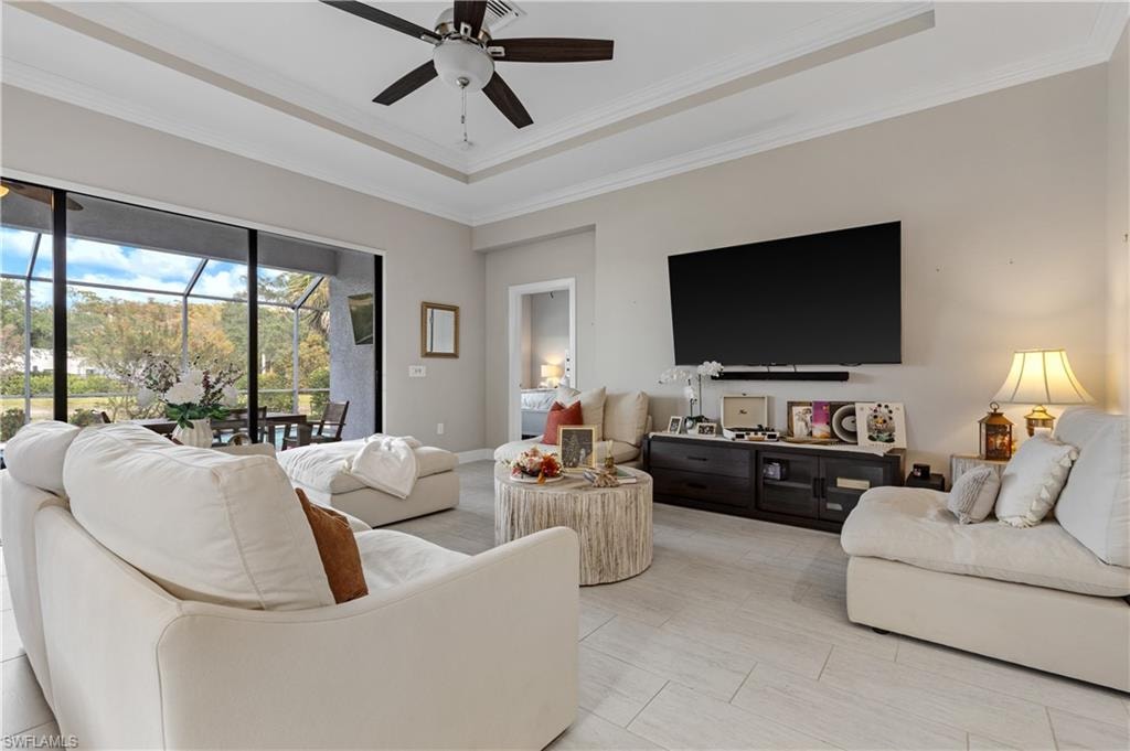 Living area with a raised ceiling, crown molding, and a ceiling fan