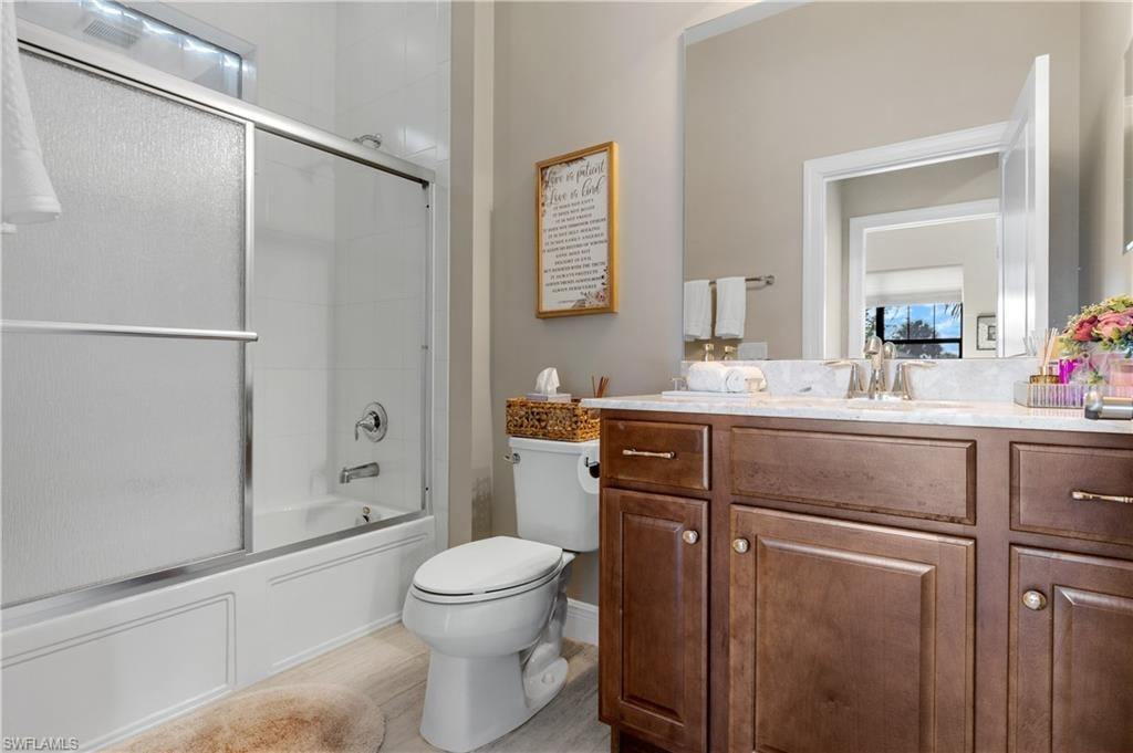 Bathroom featuring combined bath / shower with glass door and vanity