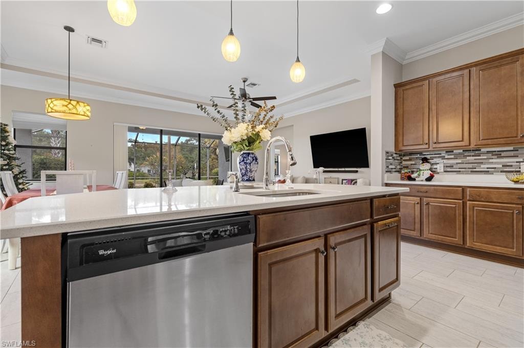 Kitchen with stainless steel dishwasher, crown molding, pendant lighting, tasteful backsplash, and light stone countertops