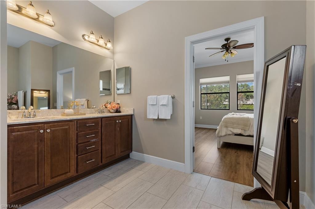Bathroom with double vanity, ensuite bath, wood finish floors, ornamental molding, and a ceiling fan