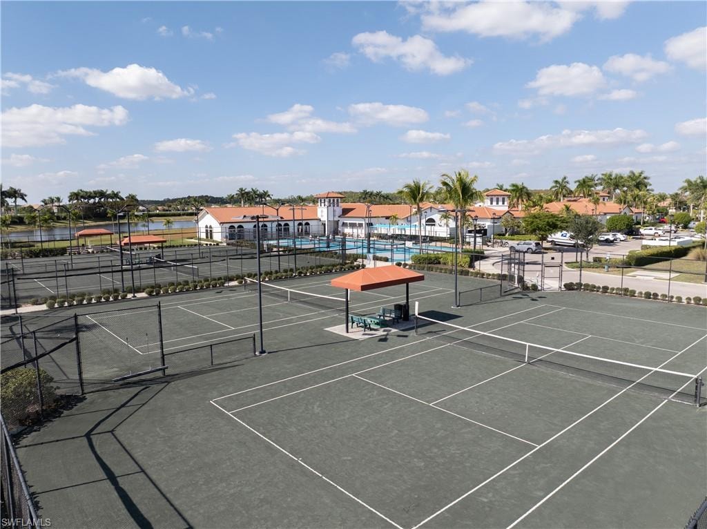 View of tennis court featuring community basketball court and a water view