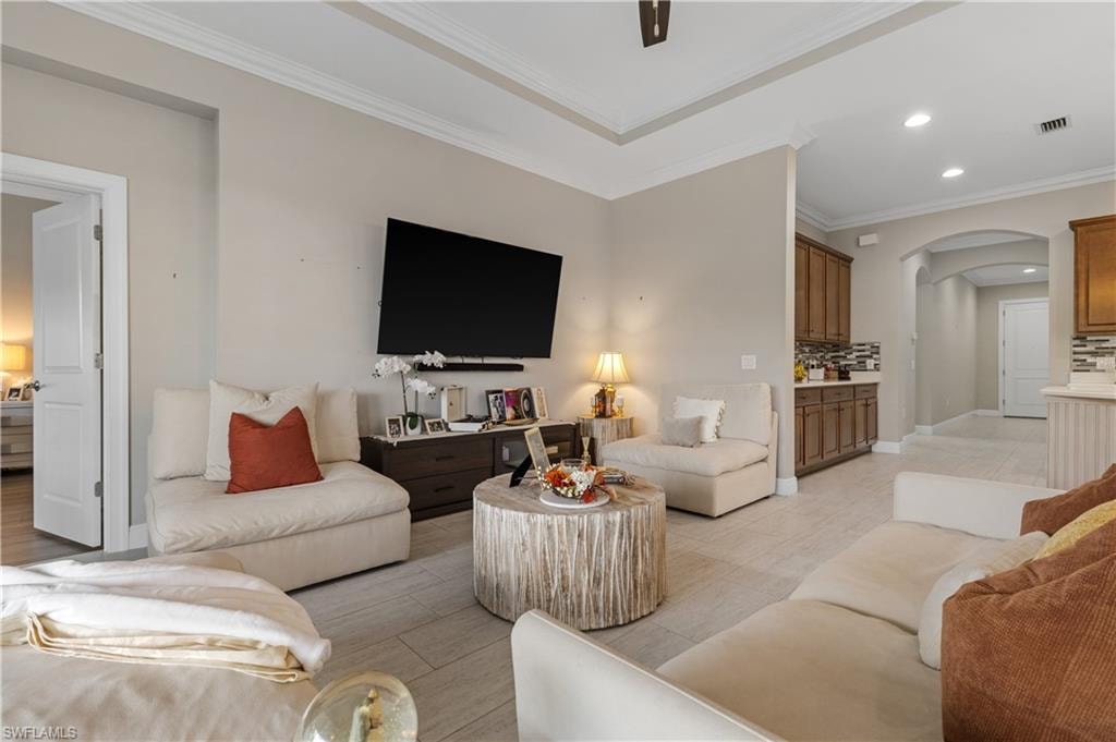 Living area with recessed lighting, ornamental molding, and arched walkways