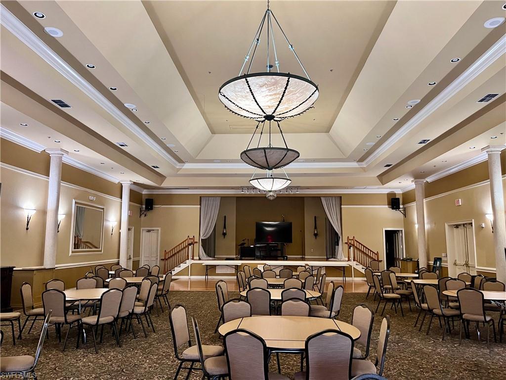Community Dining room featuring stairway, ornamental molding, a raised ceiling, and ornate columns