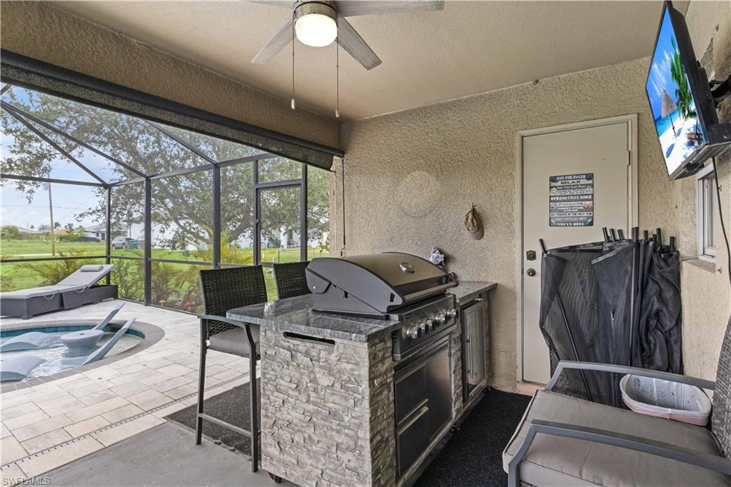 A covered outdoor cooking area with a built-in grill provides an amazing space for dining al fresco, rain or shine.